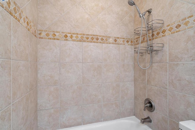 bathroom featuring toilet and tiled shower / bath