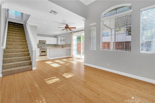 unfurnished living room with ceiling fan, crown molding, and light hardwood / wood-style floors