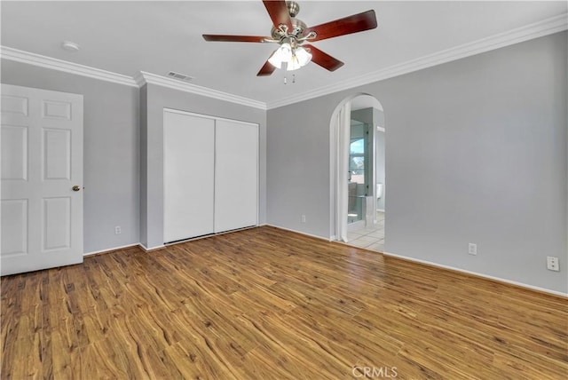 unfurnished bedroom featuring ceiling fan, light wood-type flooring, a closet, and ornamental molding