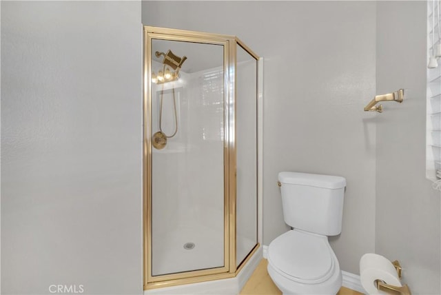 bathroom featuring toilet and a shower with door