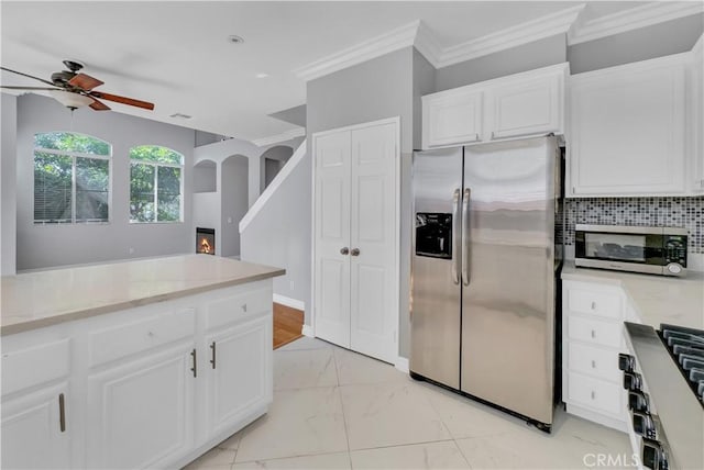 kitchen featuring ceiling fan, appliances with stainless steel finishes, backsplash, light stone countertops, and white cabinets