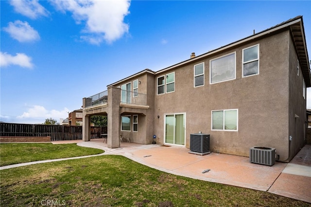 rear view of house with central AC, a balcony, a patio, and a yard