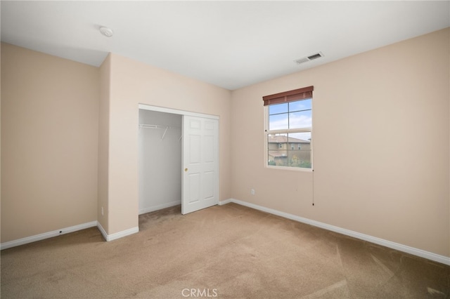 unfurnished bedroom featuring light colored carpet and a closet