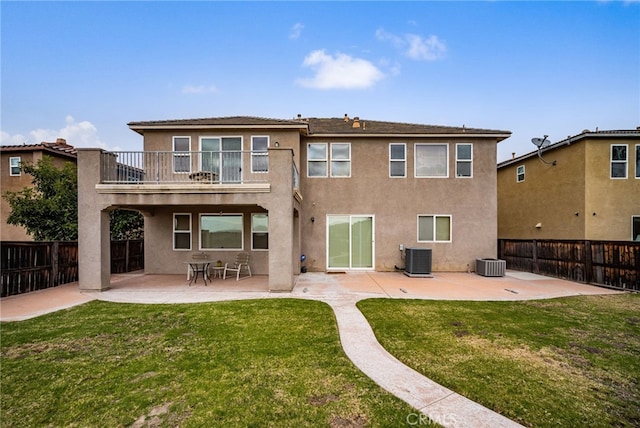 rear view of property with a balcony, cooling unit, a lawn, and a patio