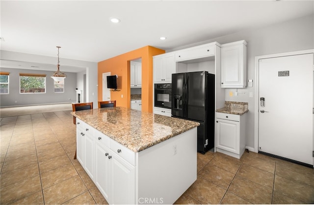 kitchen with pendant lighting, black appliances, a kitchen island, white cabinets, and light stone counters