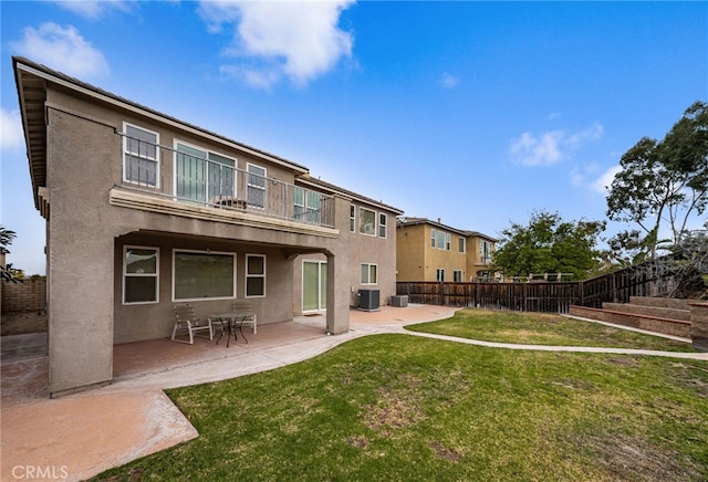 back of house featuring a balcony, cooling unit, a lawn, and a patio