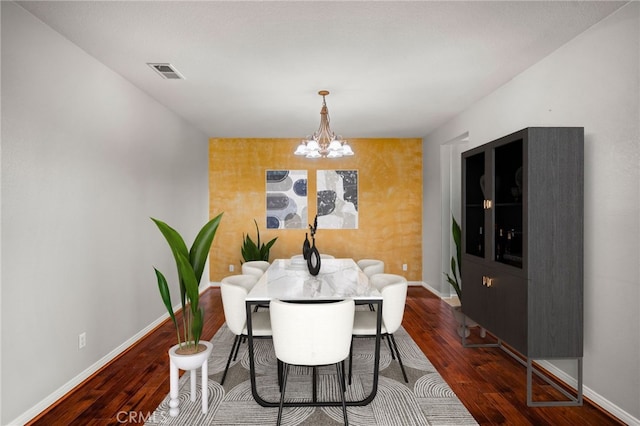 dining space with dark hardwood / wood-style flooring and a notable chandelier