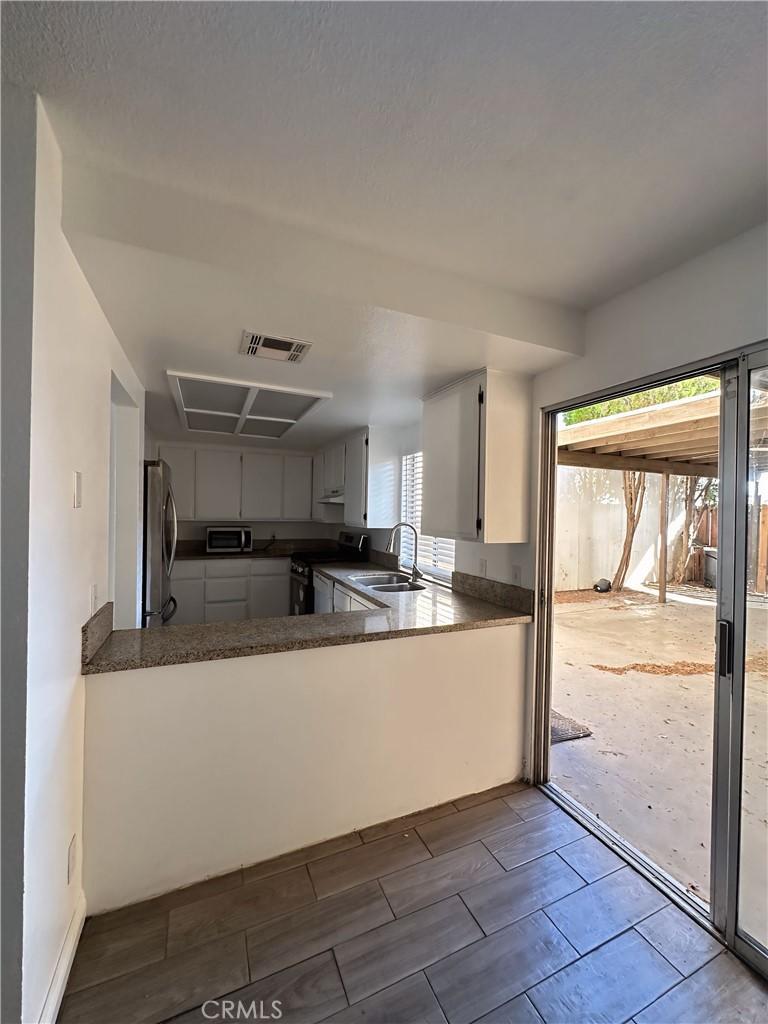 kitchen featuring kitchen peninsula, sink, stainless steel appliances, and white cabinetry