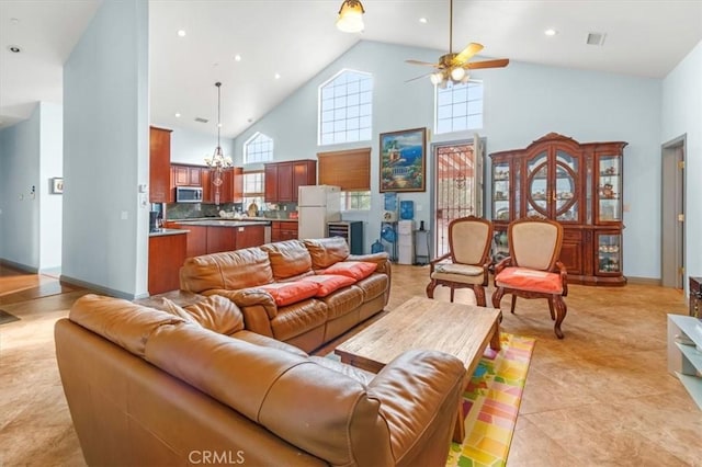 living room with high vaulted ceiling, light tile patterned flooring, and ceiling fan with notable chandelier