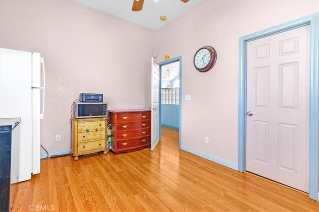 bedroom featuring light hardwood / wood-style floors, ceiling fan, and white fridge