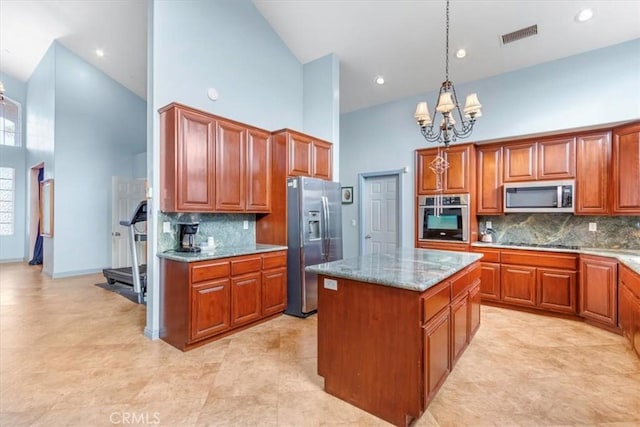 kitchen featuring a center island, stainless steel appliances, a towering ceiling, and an inviting chandelier