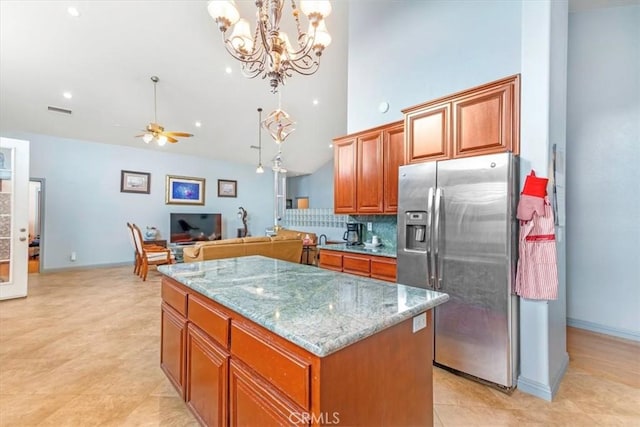 kitchen with tasteful backsplash, a center island, hanging light fixtures, stainless steel fridge, and ceiling fan with notable chandelier