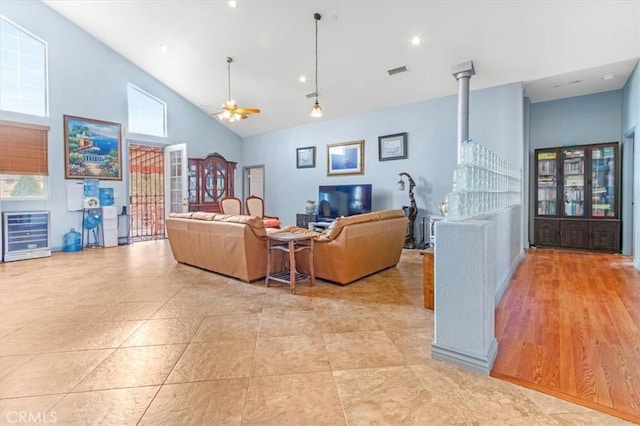 living room with ceiling fan, a towering ceiling, and beverage cooler