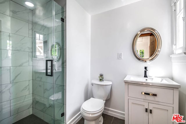 bathroom featuring toilet, tile patterned floors, a shower with shower door, and vanity