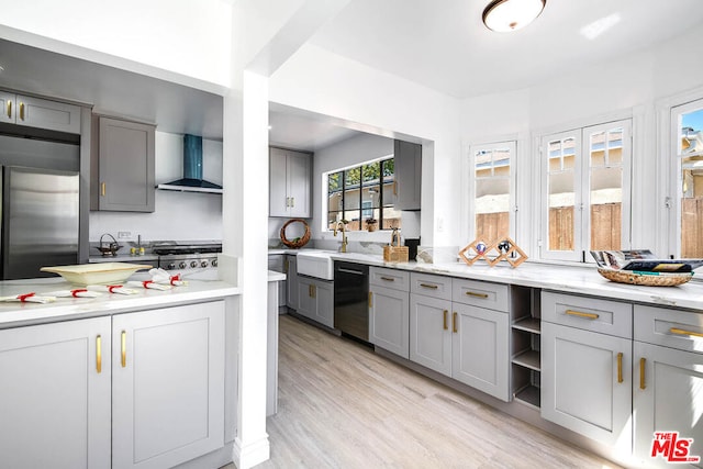 kitchen featuring gray cabinetry, wall chimney exhaust hood, dishwasher, and stainless steel refrigerator