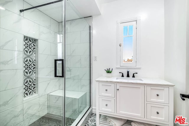 bathroom with a shower with shower door and vanity