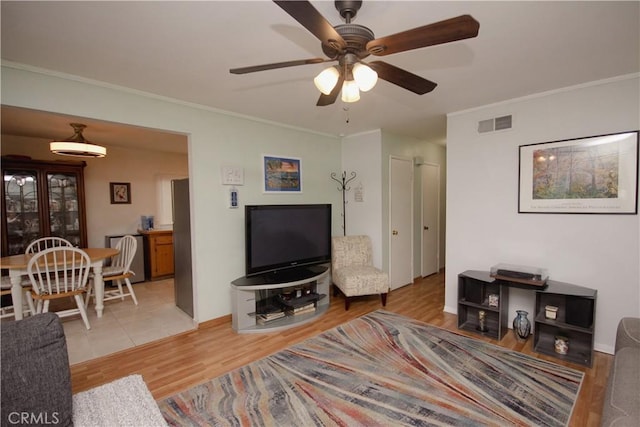 living room with ceiling fan, light wood-type flooring, and crown molding