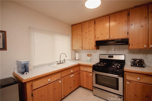 kitchen with stainless steel gas range, light tile patterned floors, backsplash, and sink