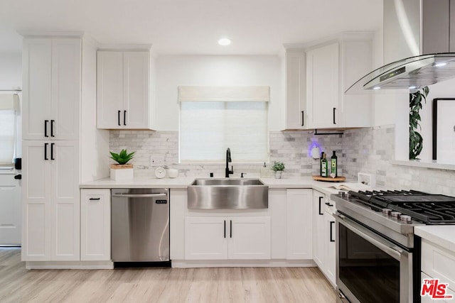 kitchen featuring stainless steel appliances, decorative backsplash, sink, white cabinetry, and range hood