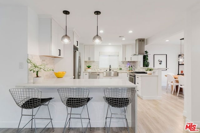 kitchen featuring kitchen peninsula, white cabinets, island exhaust hood, and pendant lighting