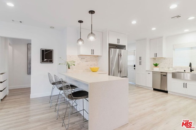 kitchen featuring light hardwood / wood-style floors, tasteful backsplash, white cabinetry, appliances with stainless steel finishes, and sink