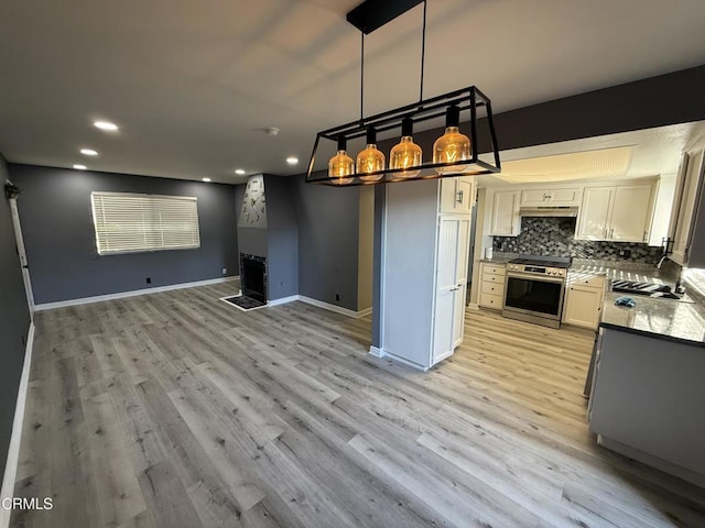 kitchen featuring backsplash, hanging light fixtures, stainless steel stove, white cabinets, and sink