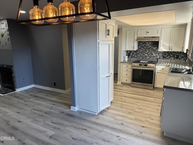 kitchen with white cabinetry, hanging light fixtures, stainless steel stove, light hardwood / wood-style flooring, and sink