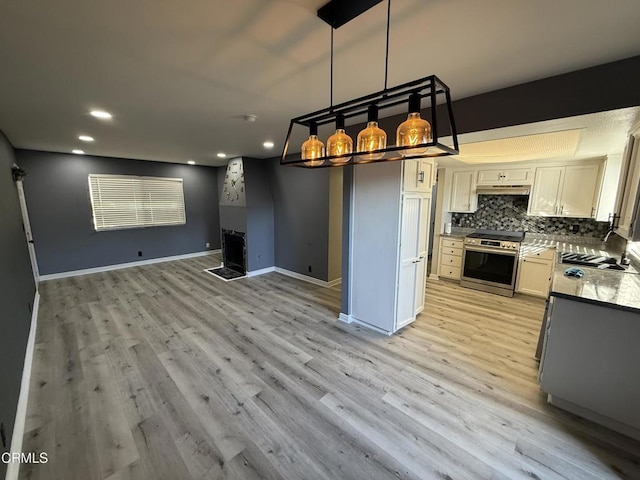 kitchen with tasteful backsplash, hanging light fixtures, stainless steel range oven, white cabinets, and sink