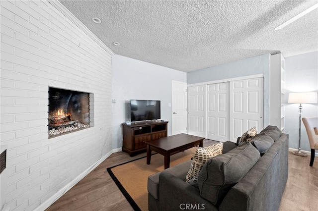 living room with brick wall, a textured ceiling, and light wood-type flooring