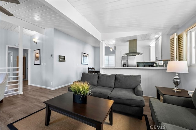 living room with beam ceiling, hardwood / wood-style flooring, and sink