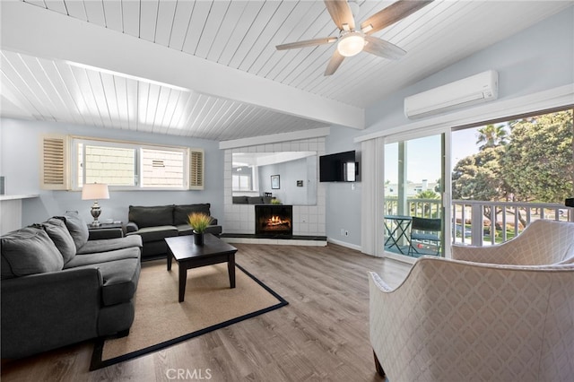 living room with ceiling fan, wood-type flooring, a wall unit AC, and a healthy amount of sunlight