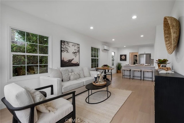 living room with light wood-type flooring, plenty of natural light, and an AC wall unit