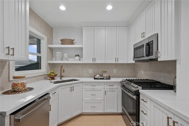 kitchen featuring tasteful backsplash, sink, appliances with stainless steel finishes, white cabinets, and light stone counters