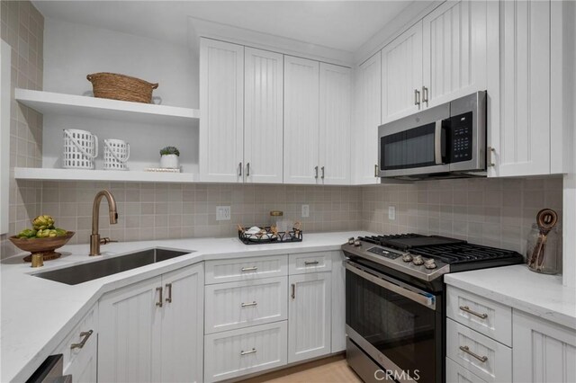 kitchen featuring decorative backsplash, sink, stainless steel appliances, and white cabinetry