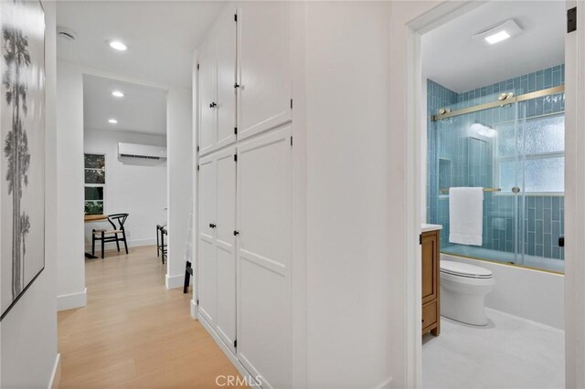 hallway featuring light hardwood / wood-style flooring and an AC wall unit