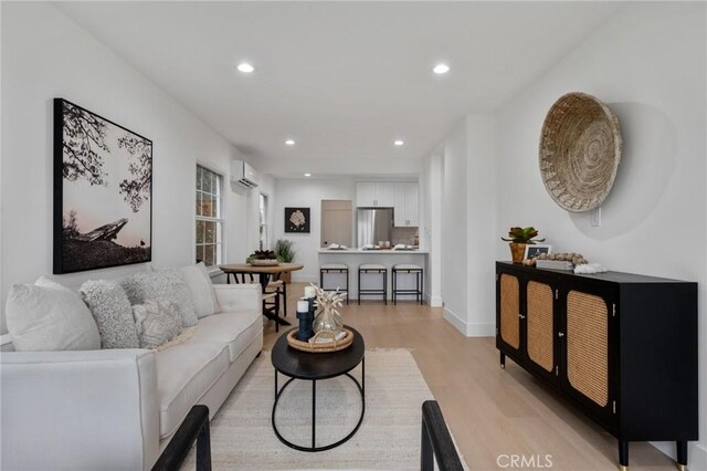 living room featuring light hardwood / wood-style flooring and an AC wall unit