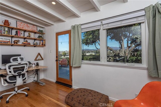 home office with light hardwood / wood-style floors and beamed ceiling