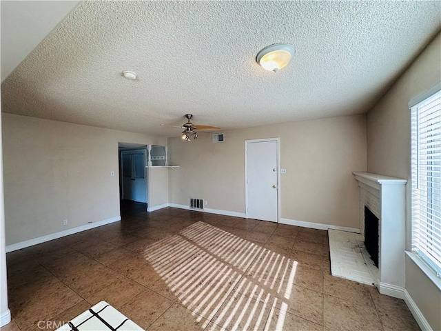 unfurnished living room with ceiling fan, a textured ceiling, tile patterned floors, and a fireplace