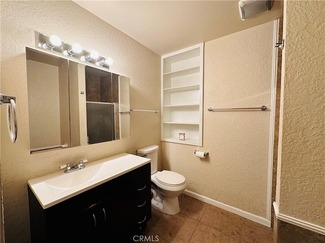 bathroom with toilet, vanity, tile patterned floors, built in shelves, and a shower with door