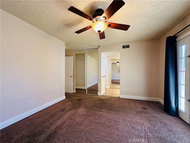 unfurnished room with ceiling fan, a wealth of natural light, a textured ceiling, and carpet flooring