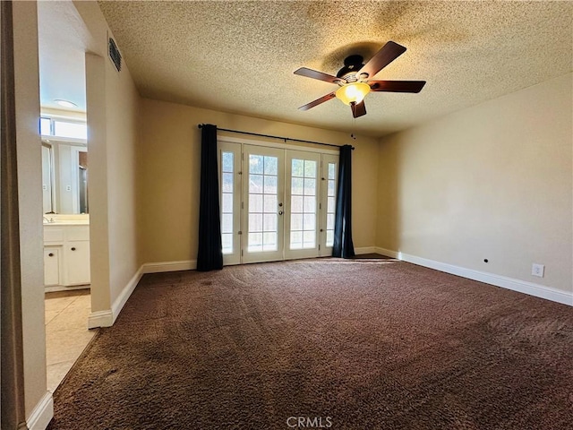 empty room with light carpet, ceiling fan, french doors, and a textured ceiling