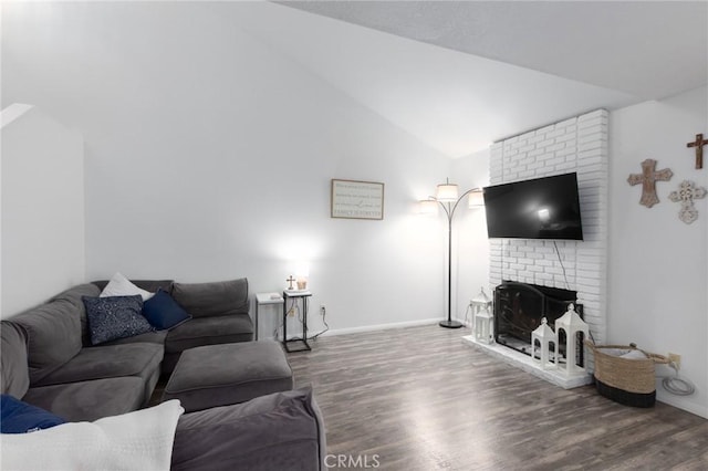 living room featuring vaulted ceiling, a brick fireplace, and dark hardwood / wood-style flooring