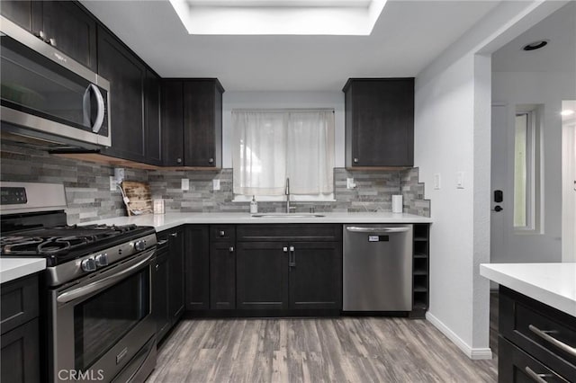 kitchen featuring appliances with stainless steel finishes, light hardwood / wood-style floors, backsplash, and sink