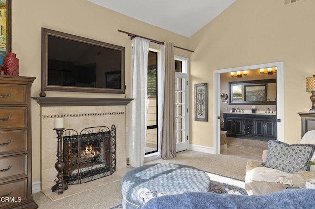 living room featuring vaulted ceiling, a fireplace, and light colored carpet