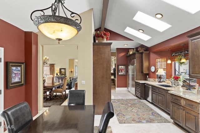 kitchen featuring decorative light fixtures, dishwasher, lofted ceiling with skylight, light stone countertops, and sink