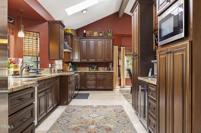 kitchen with lofted ceiling with skylight, sink, dark brown cabinetry, hanging light fixtures, and appliances with stainless steel finishes