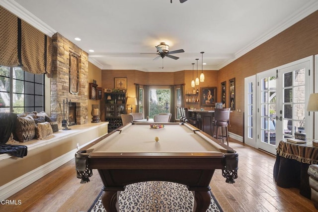 playroom with ceiling fan, light hardwood / wood-style floors, a stone fireplace, french doors, and pool table