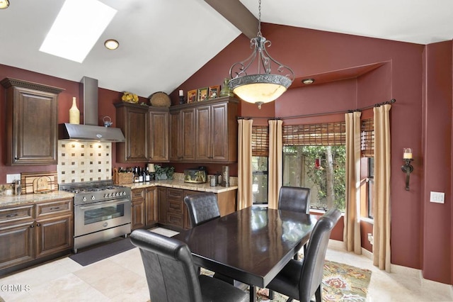 kitchen with pendant lighting, wall chimney exhaust hood, decorative backsplash, high end stove, and light stone counters