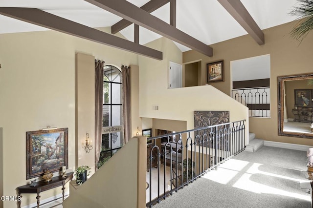 hall featuring beamed ceiling, carpet, an upstairs landing, and high vaulted ceiling