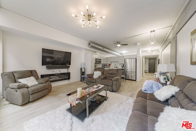 living room featuring ceiling fan with notable chandelier and light hardwood / wood-style floors